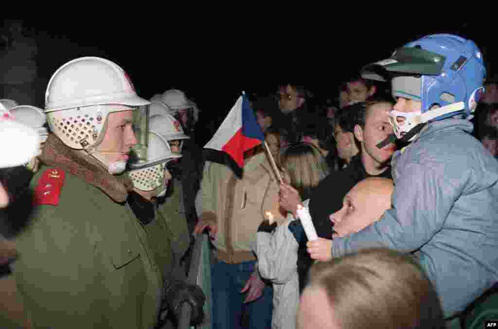 A man carrying his son and a Czechoslovak flag faces riot police on November 19 alongside hundreds of other protesters.