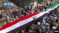 Protesters hold Syrian flags during a rally in the district of Homs on September 2.