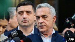 Calin Georgescu (right) talks to the media after filing his candidacy for the Romanian presidential election on March 7. His ally, far-right leader George Simion (left) is in the background. 