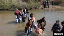 Alawite Syrians, who fled the violence in western Syria, walk in the water of the Nahr al-Kabir River in Akkar, Lebanon, on March 11.