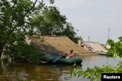 Местный житель сидит в надувной лодке в зоне затопления города Голая Пристань Херсонской области, 8 июня 2023 года