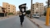 A member of the Islamic State militants waves an IS flag in the Syrian city of Raqqa. (file photo)