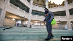 A specialist wearing a protective mask sprays disinfectant as he sanitizes the Moscow Cathedral Mosque to prevent the spread of the coronavirus in Moscow on March 27.